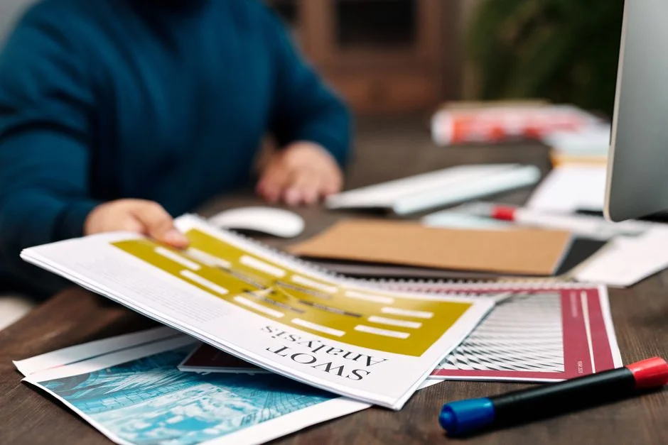 Overhead view of business chart with red notebook and colored pencils on table.